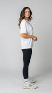 women wearing a white oversized tee with black leggings. side view