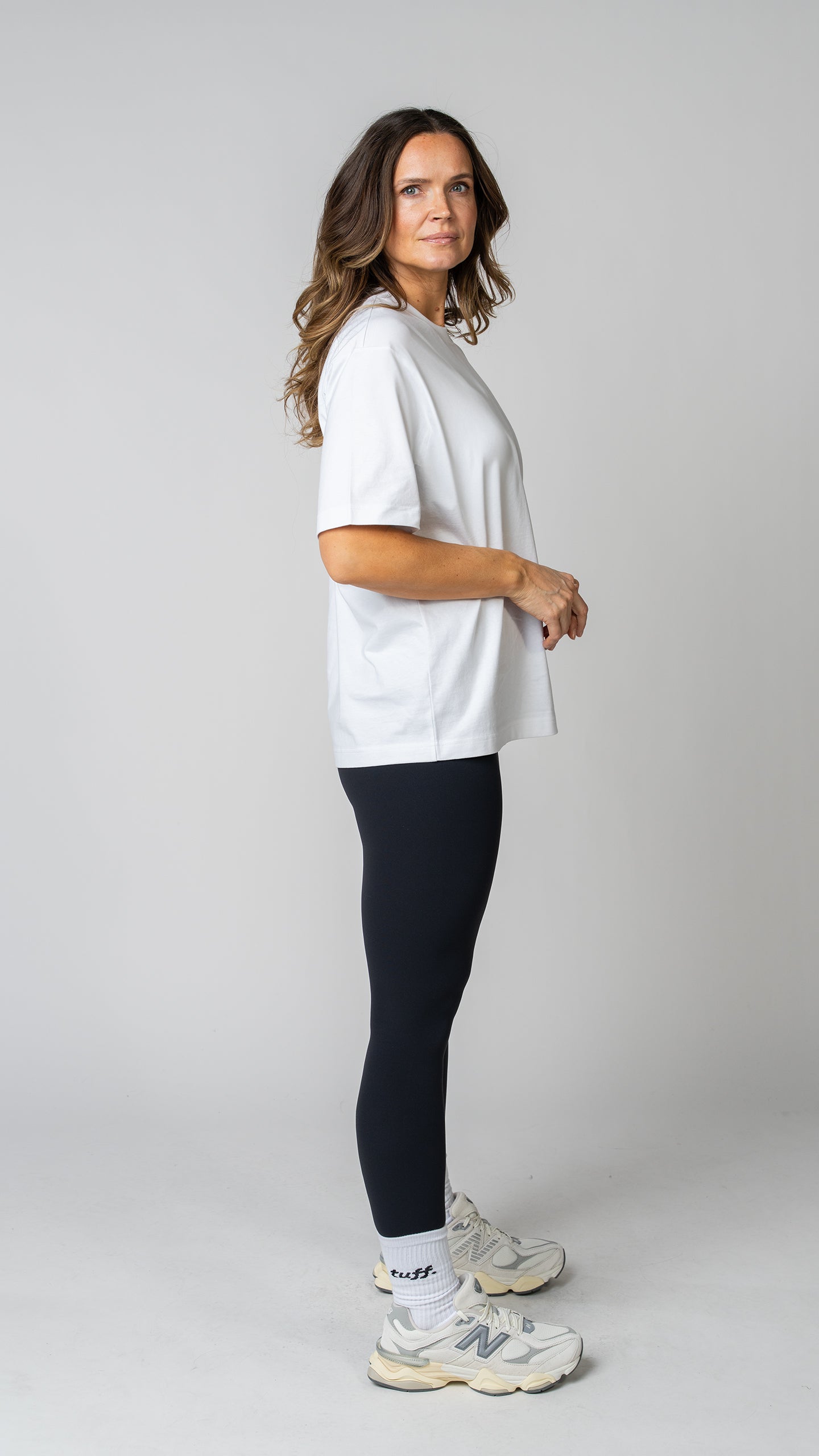women wearing a white oversized tee with black leggings. side view