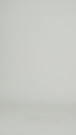 Video of a woman wearing a plain white t-shirt and dark tights walking into a studio backdrop. 